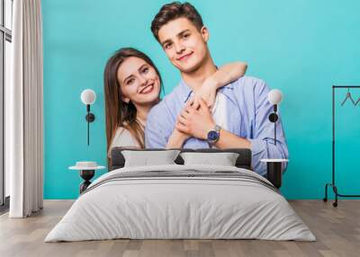 Young hug couple smiling on a blue background Wall mural